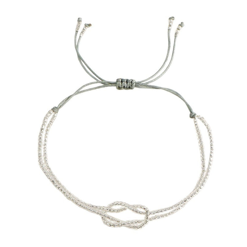 Bracelet fin à perles miyuki blanches avec nœud central en forme de symbole, cordon gris ajustable à coulisse.