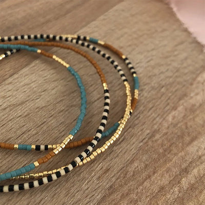 Bracelet à perles Miyuki fines turquoise, or et brun avec cordon ajustable, style bohème chic.
