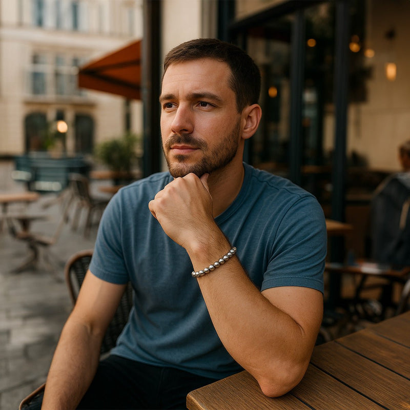 Bracelet élastique à perles polies argentées en acier inoxydable porté au poignet masculin.