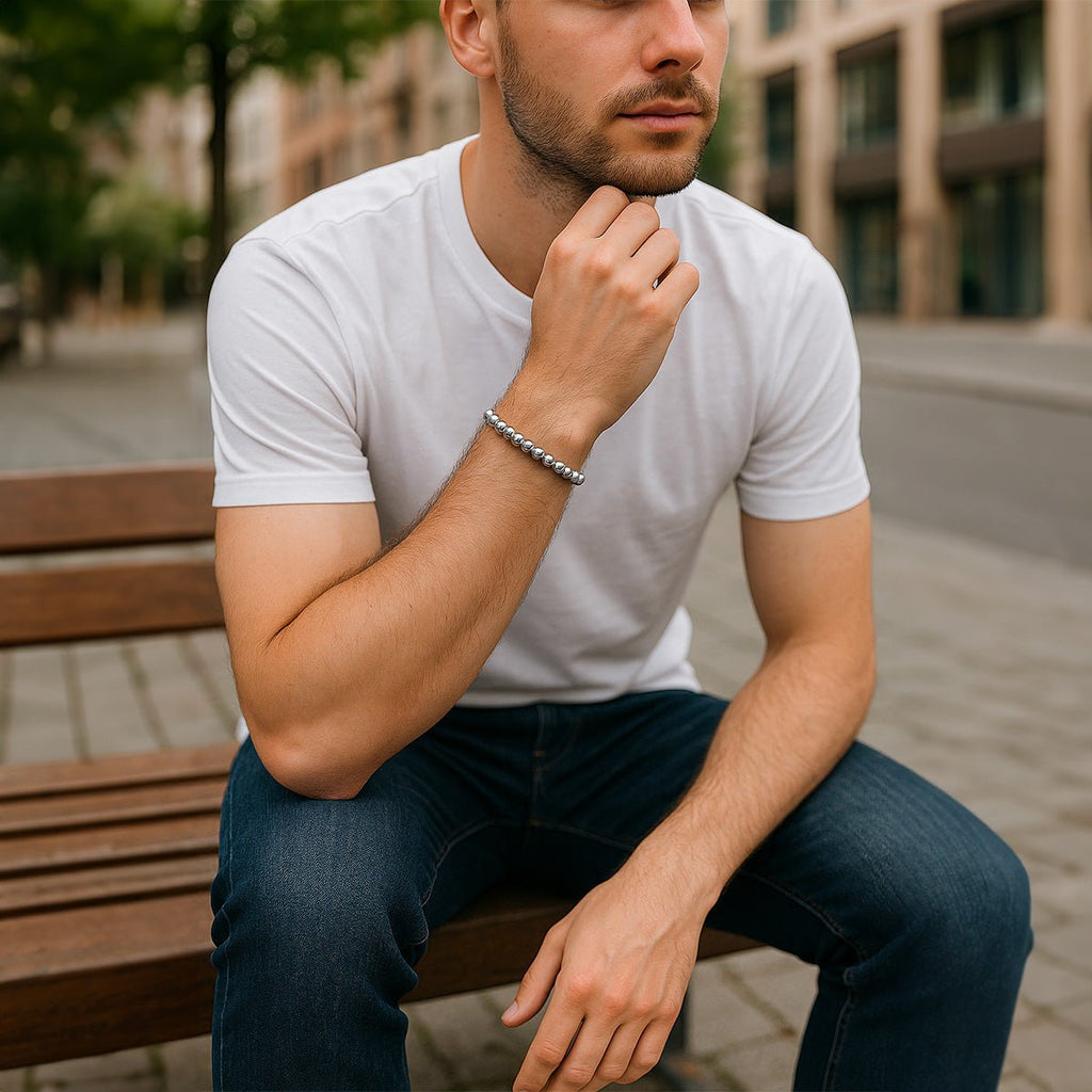 Bracelet élastique à perles polies en acier inoxydable argenté porté au poignet, style casual masculin.