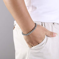 Bracelet élastique en perles polies d'acier inoxydable argenté porté au poignet, style moderne et masculin.