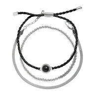 Bracelet trio avec perles dorées, cordon noir tressé et chaîne en acier inoxydable argenté.
