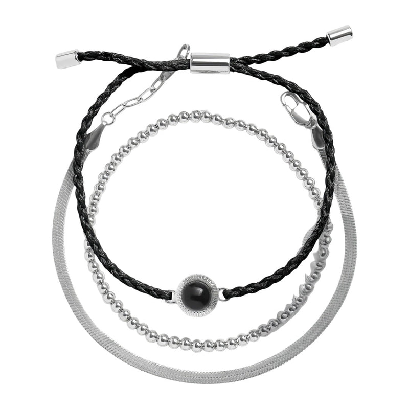 Bracelet trio avec perles dorées, cordon noir tressé et chaîne en acier inoxydable argenté.