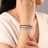 Bracelet femme à cordon tressé noir avec perles dorées et médaille ronde en acier inoxydable, style trio élégant.