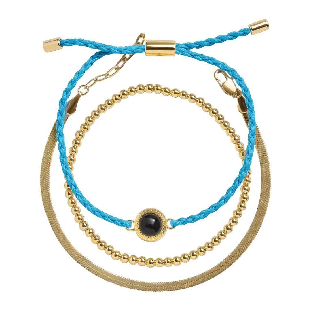 Bracelet trio cordon bleu tressé et perles dorées en acier inoxydable avec détail projection photo noir au centre.