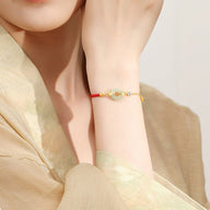 Bracelet en fil rouge avec pierre de jade verte et argent 925, style délicat et minimaliste, porté au poignet féminin.