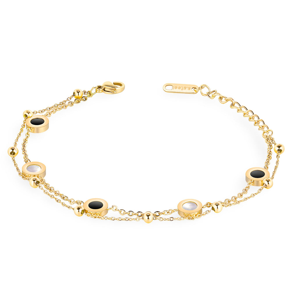 Bracelet ajustable doré en titane avec cinq motifs ronds noirs et blancs alternés sur chaîne fine.