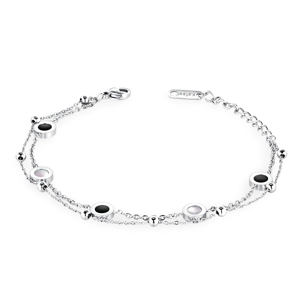 Bracelet fin ajustable en argent avec petits motifs ronds noirs et blancs espacés sur chaîne délicate.