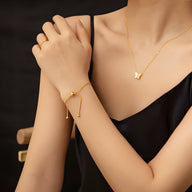 Bracelet ajustable en titane doré avec cordon fin et pendentif papillon minimaliste, porté à la main féminine.