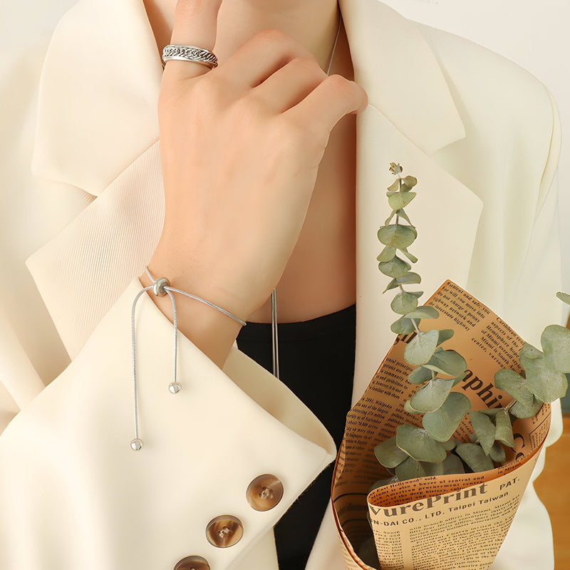 Bracelet ajustable en titane doré fin avec extrémités seuils et cordon élégant, style minimaliste.