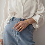 Bracelet ajustable fin en titane doré porté avec bague assortie sur une main féminine, style minimaliste.