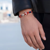 Bracelet ancre en coton rouge et bleu avec ancre en acier inoxydable, style maritime, porté au poignet homme.