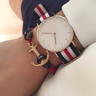 Montre bracelet avec cadran blanc et boîtier doré, bracelet tissu rayé bleu, blanc et rouge, bijou ancre dorée en coton noir .