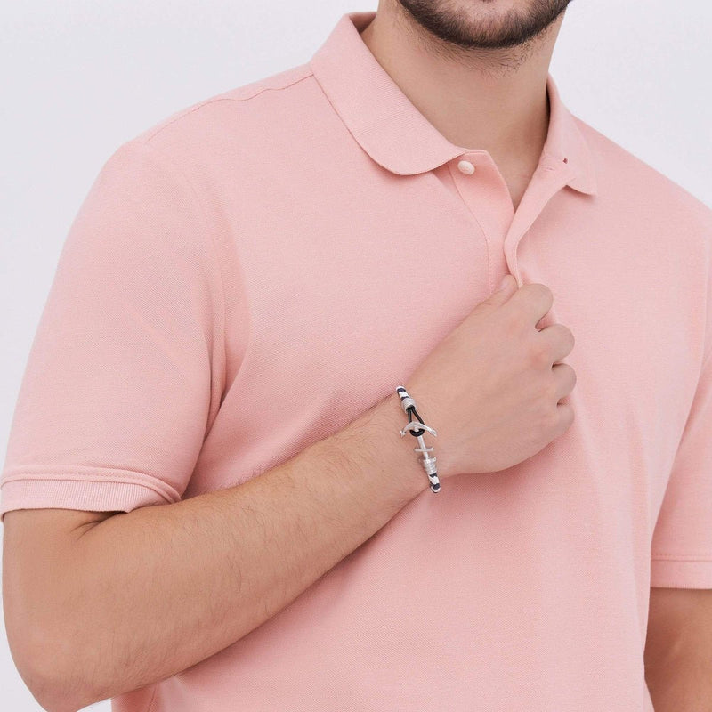 Bracelet ancre en cuir blanc et bleu avec fermoir en acier inoxydable porté au poignet d'un homme en polo rose pâle.