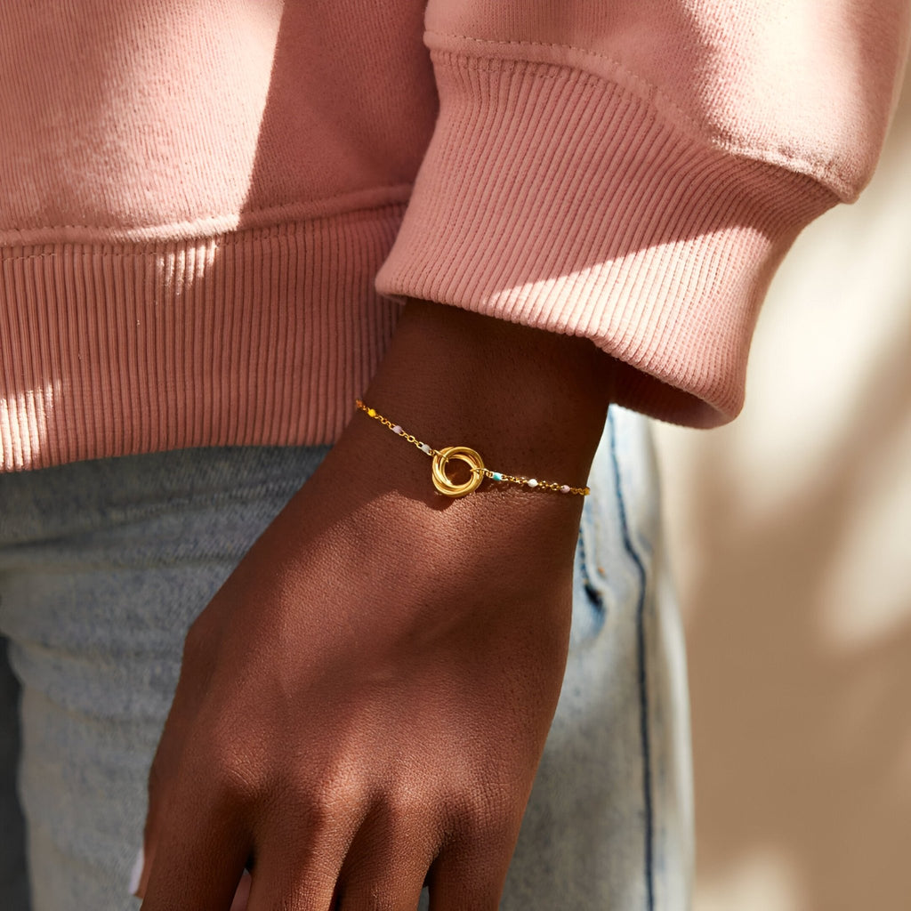 Bracelet doré fin avec deux anneaux emmêlés sur chaîne délicate pour femme.