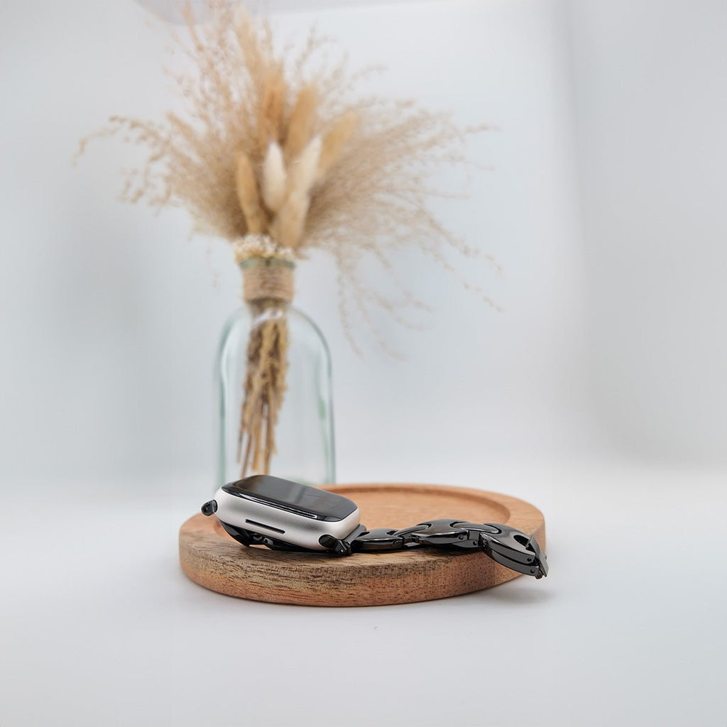 Bracelet Apple Watch femme en mailles acier noir mat, design moderne, fermoir papillon élégant.