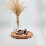 Bracelet Apple Watch en mailles marine argentées, design moderne, posé sur un support en bois rond.