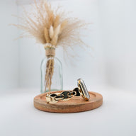 Bracelet Apple Watch à mailles marine en métal doré, design moderne et élégant sur socle en bois clair.