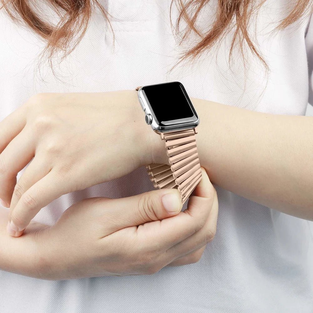 Bracelet extensible rose en acier inoxydable à maillons pour Apple Watch, sans fermoir, porté au poignet féminin.