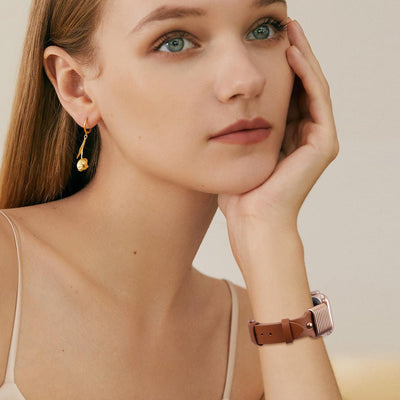 Bracelet Apple Watch en cuir marron avec boucle élégante effet ressort stylisé, porté au poignet féminin.