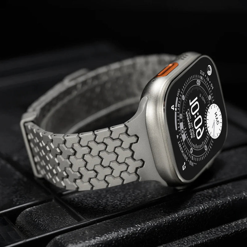 Bracelet Apple Watch en acier inoxydable gris à maillons hexagonaux, fermeture magnétique noire.