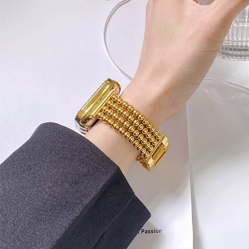 Bracelet Apple Watch en acier inoxydable doré à perles métalliques, fermoir cliquet sécurisé, design élégant féminin.