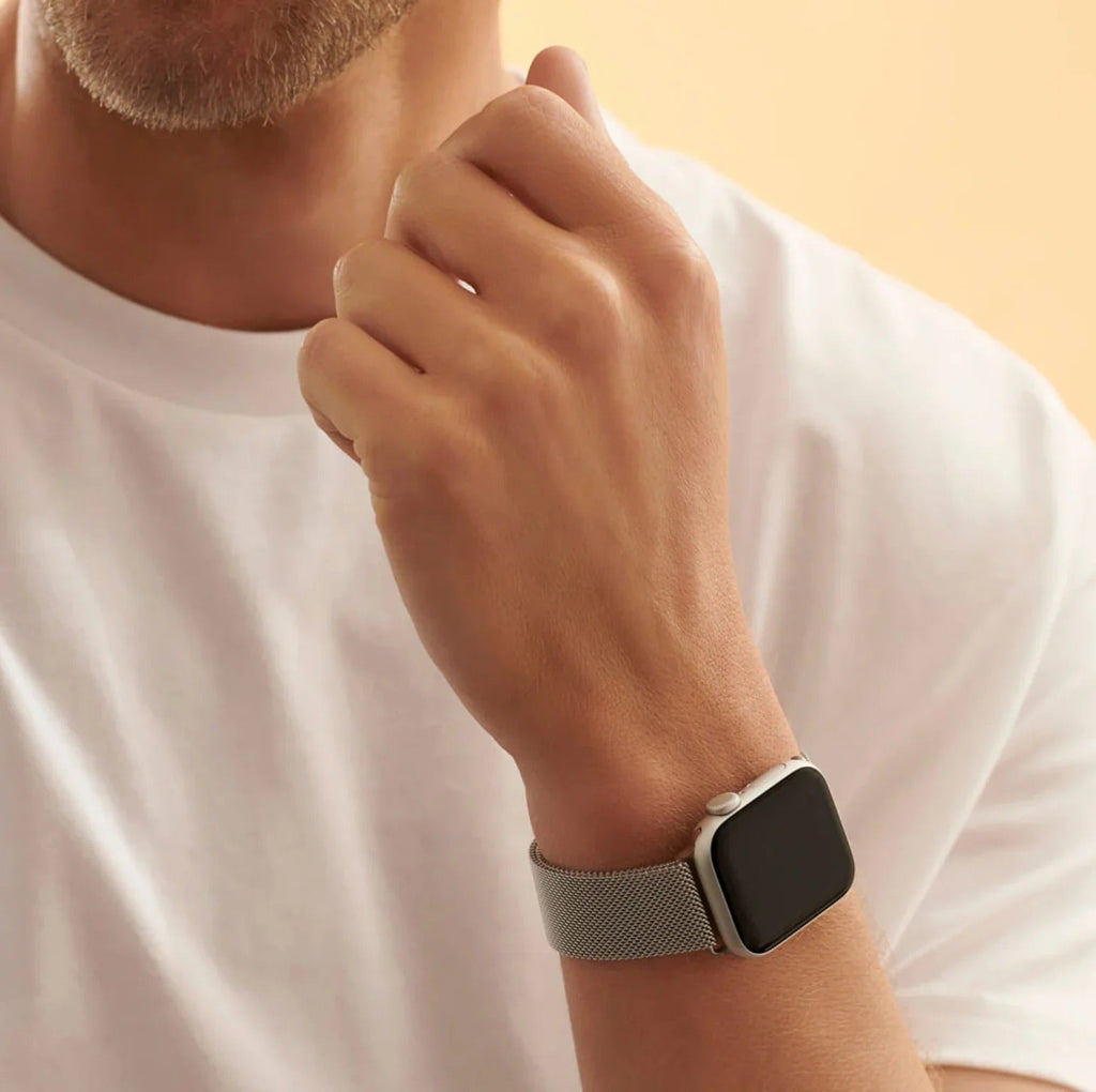 Bracelet Apple Watch en acier inoxydable gris argenté avec mailles fines tissées, style mixte, porté au poignet.