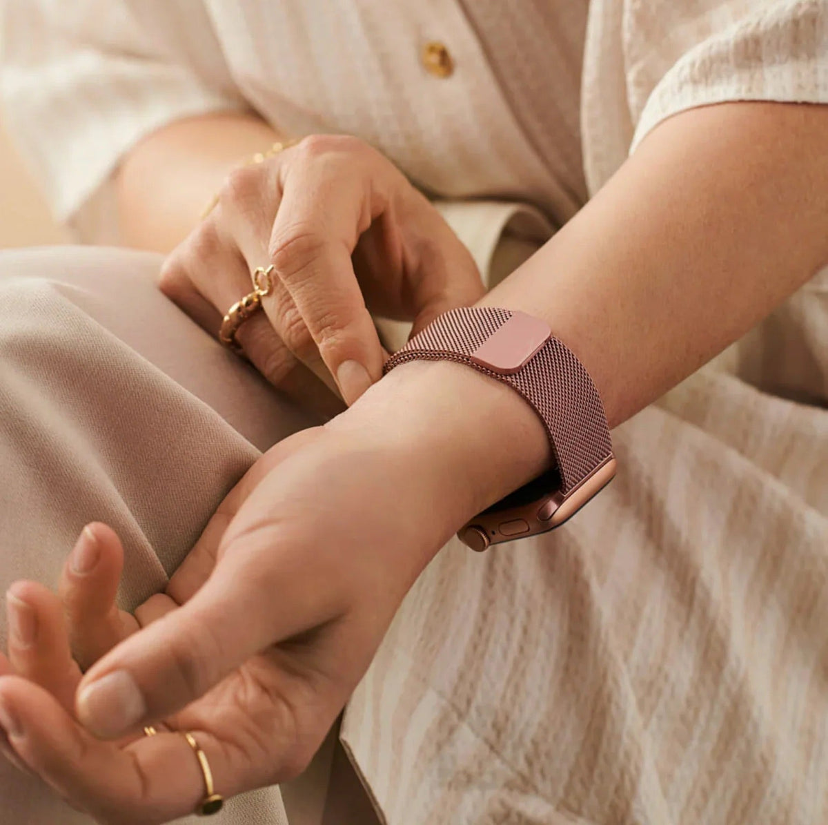 Bracelet Apple Watch en acier inoxydable rose doré avec boucle magnétique sur poignet féminin.