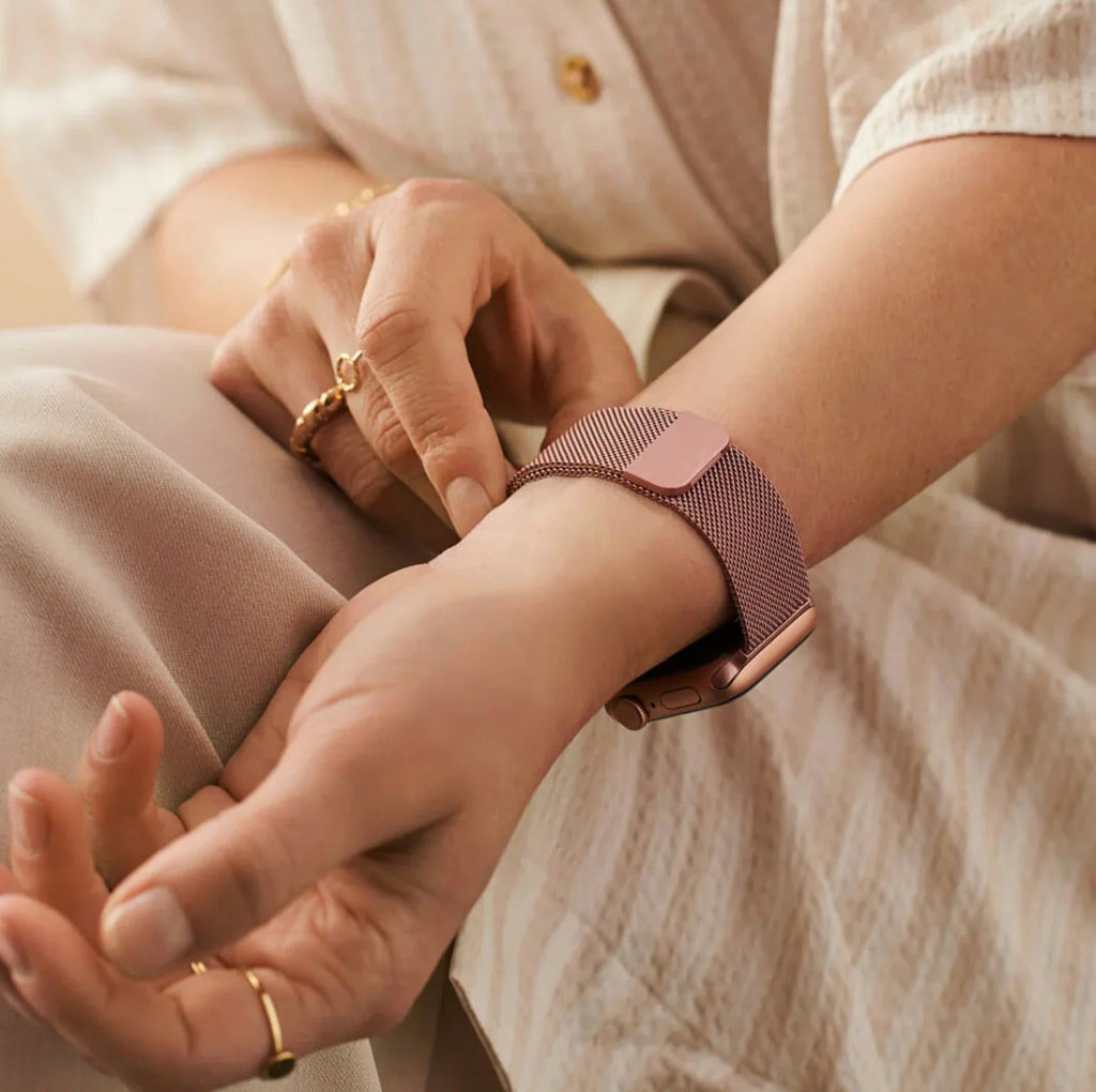 Bracelet Apple Watch en acier inoxydable rose doré avec boucle magnétique sur poignet féminin.