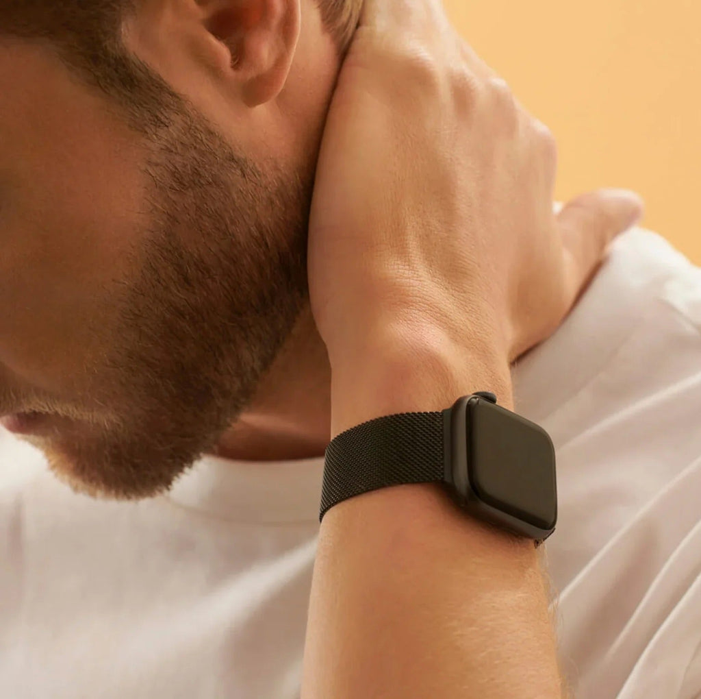 Bracelet Apple Watch en acier inoxydable noir avec fermoir magnétique, style mixte, porté au poignet.