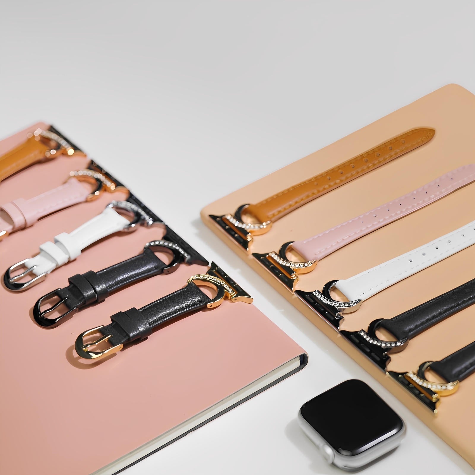 Bracelets Apple Watch en cuir couleur marron, rose, blanc et noir avec boucle en C dorée ornée de strass.