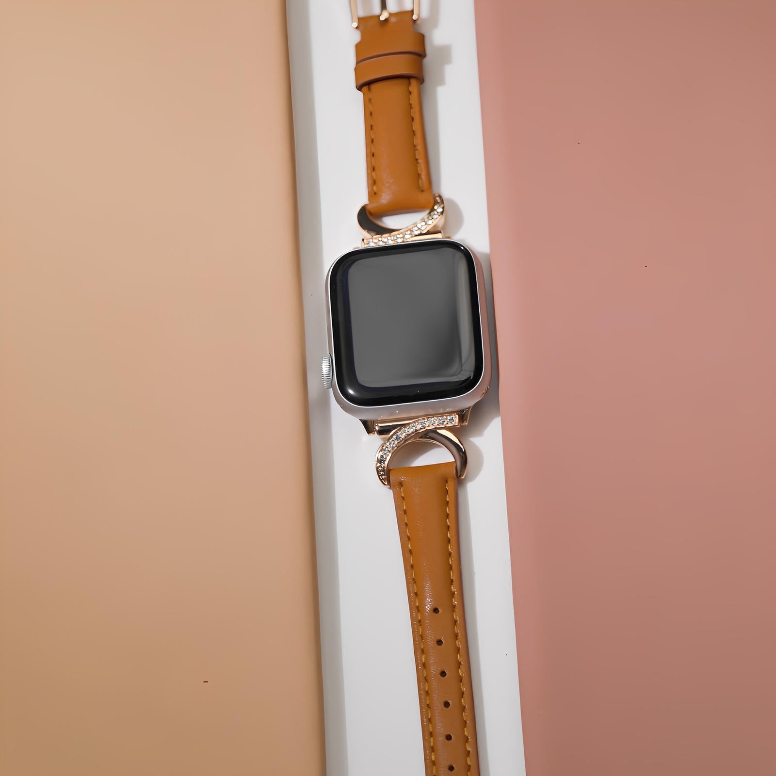 Bracelet Apple Watch en cuir camel lisse avec boucle en C dorée ornée de strass brillants.