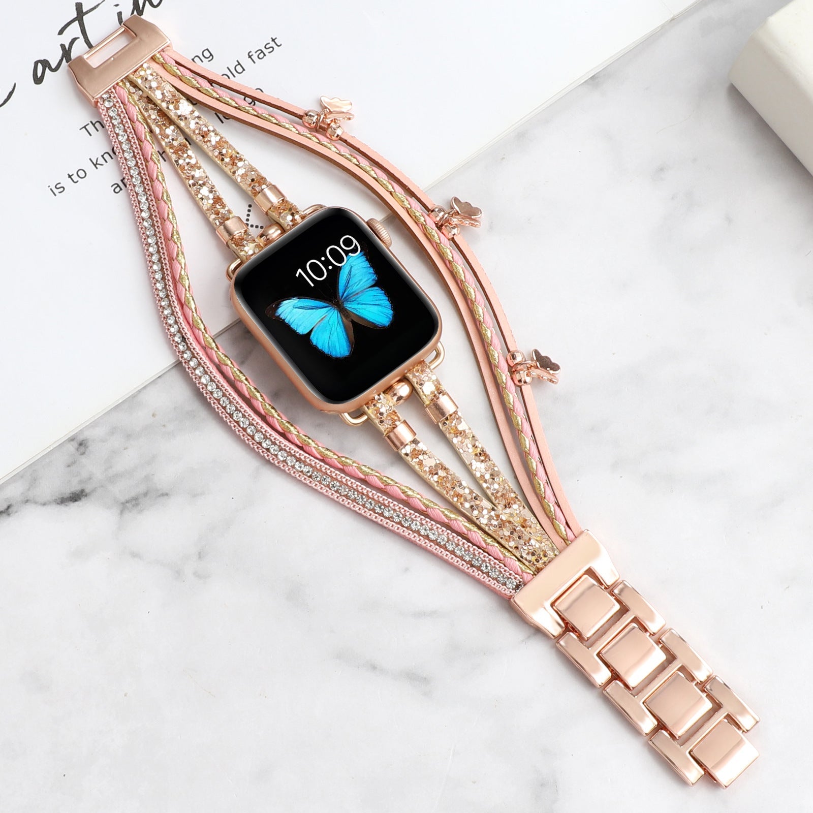 Bracelet Apple Watch multi-rangs en cuir rose et doré, papillons en strass brillants, fermoir boucle métallique rose gold.