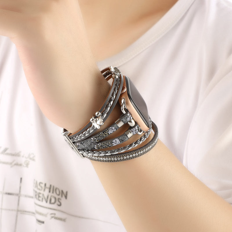 Bracelet Apple Watch multi-rangs en cuir gris avec strass brillants et petit papillon argenté, fermoir boucle élégant.