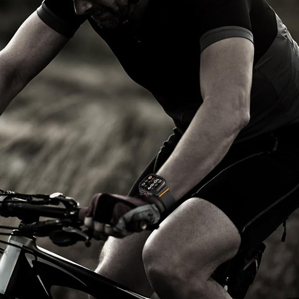 Bracelet Apple Watch en nylon noir respirant avec fermeture magnétique invisible et design ergonomique porté par un cycliste.