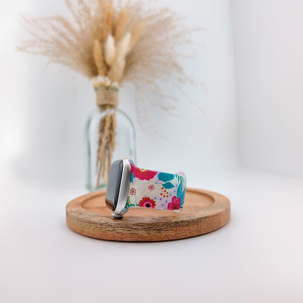 Bracelet Apple Watch en silicone blanc avec motifs floraux colorés, design féminin et moderne.