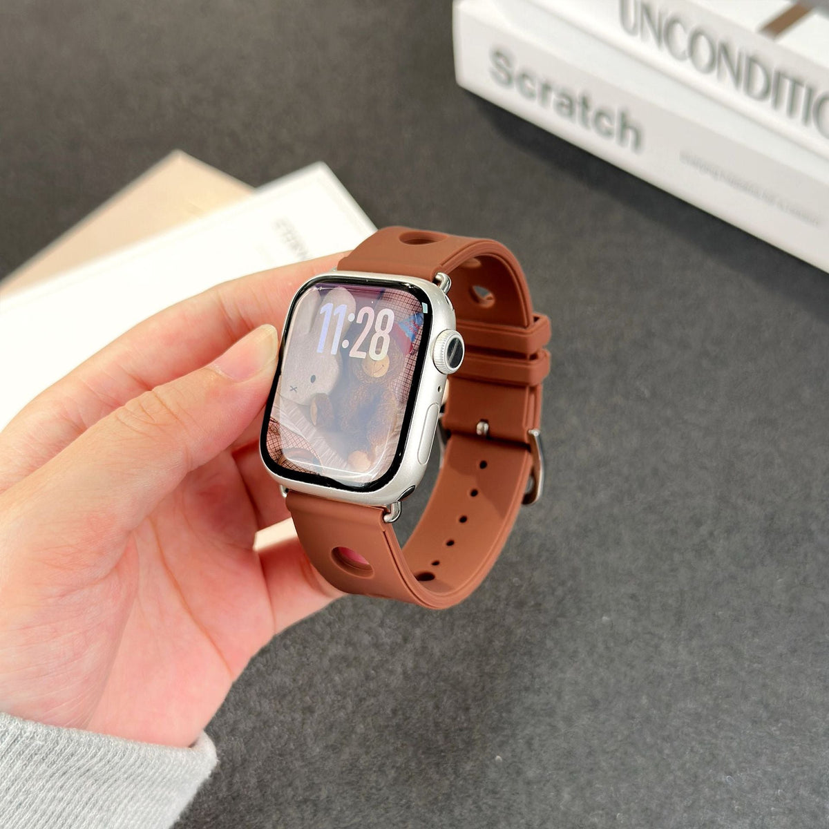 Bracelet Apple Watch en silicone perforé marron avec fermoir en acier inoxydable, design respirant et style dynamique.