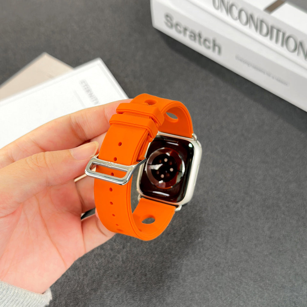 Bracelet Apple Watch orange en silicone perforé avec fermoir en acier inoxydable brillant.