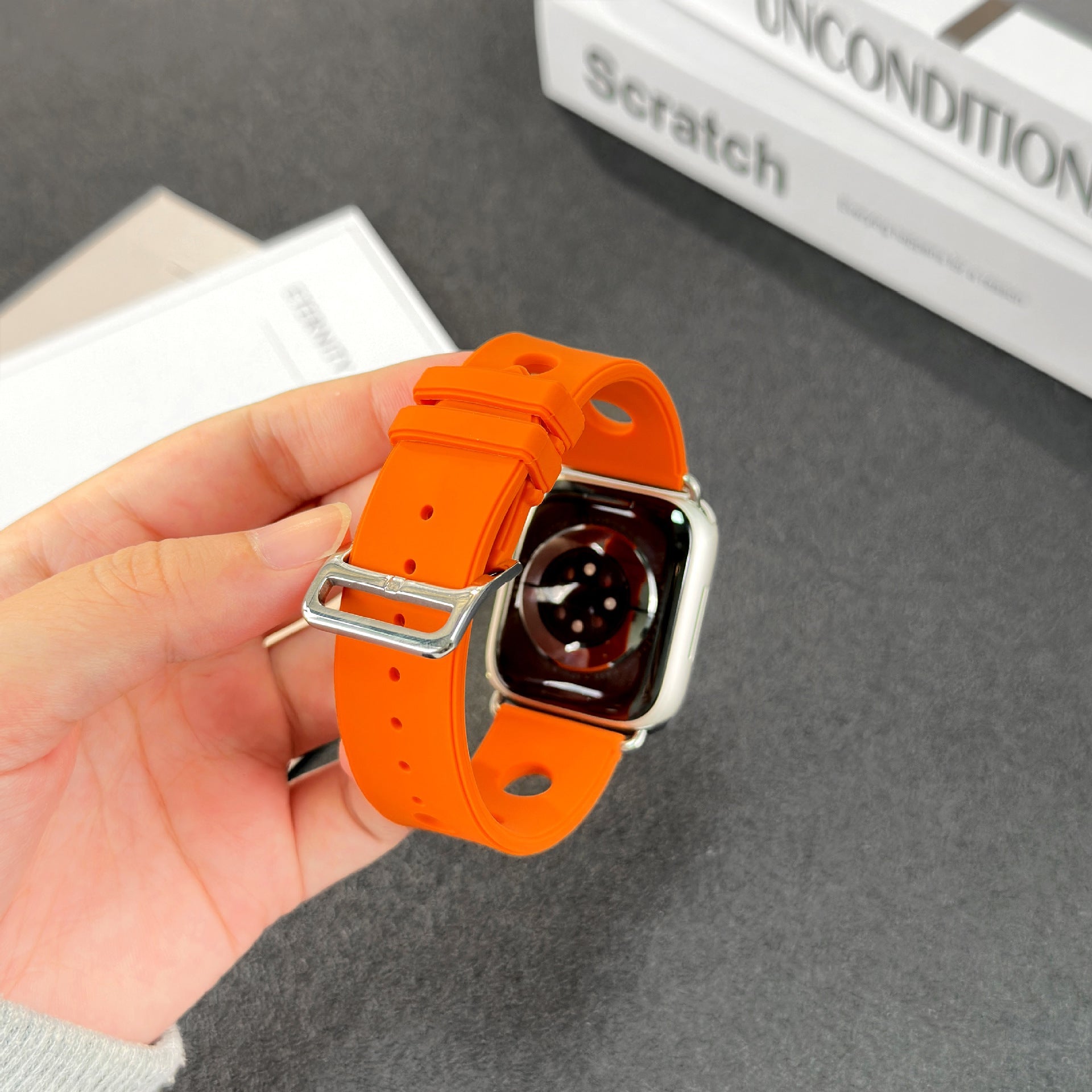 Bracelet Apple Watch orange en silicone perforé avec fermoir en acier inoxydable brillant.
