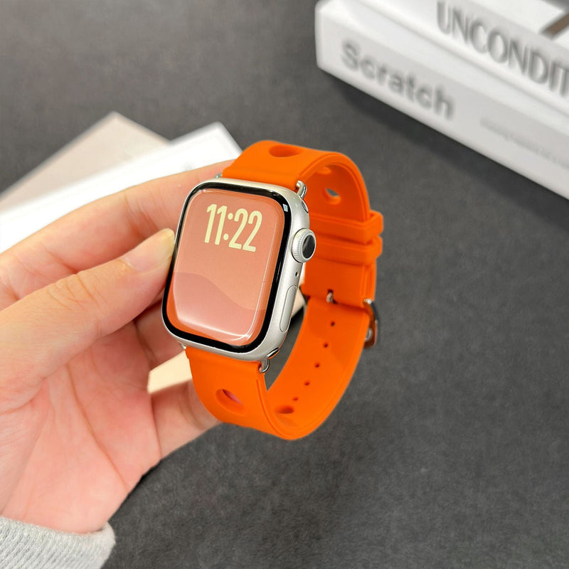 Bracelet Apple Watch en silicone orange vif avec perforations, fermoir en acier inoxydable, style sportif et respirant.