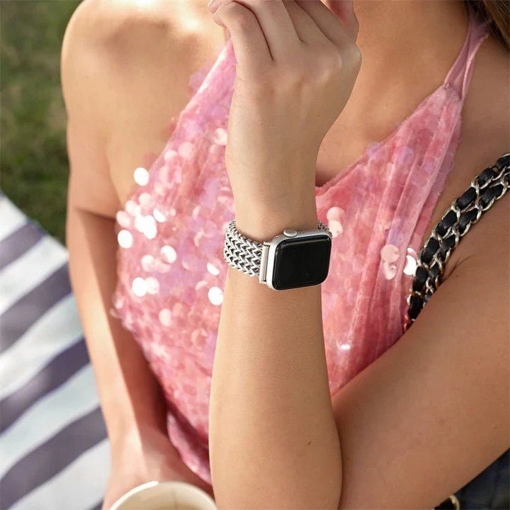 Bracelet maille Spiga argenté brillant pour Apple Watch, style raffiné et moderne, porté au poignet féminin avec robe rose.