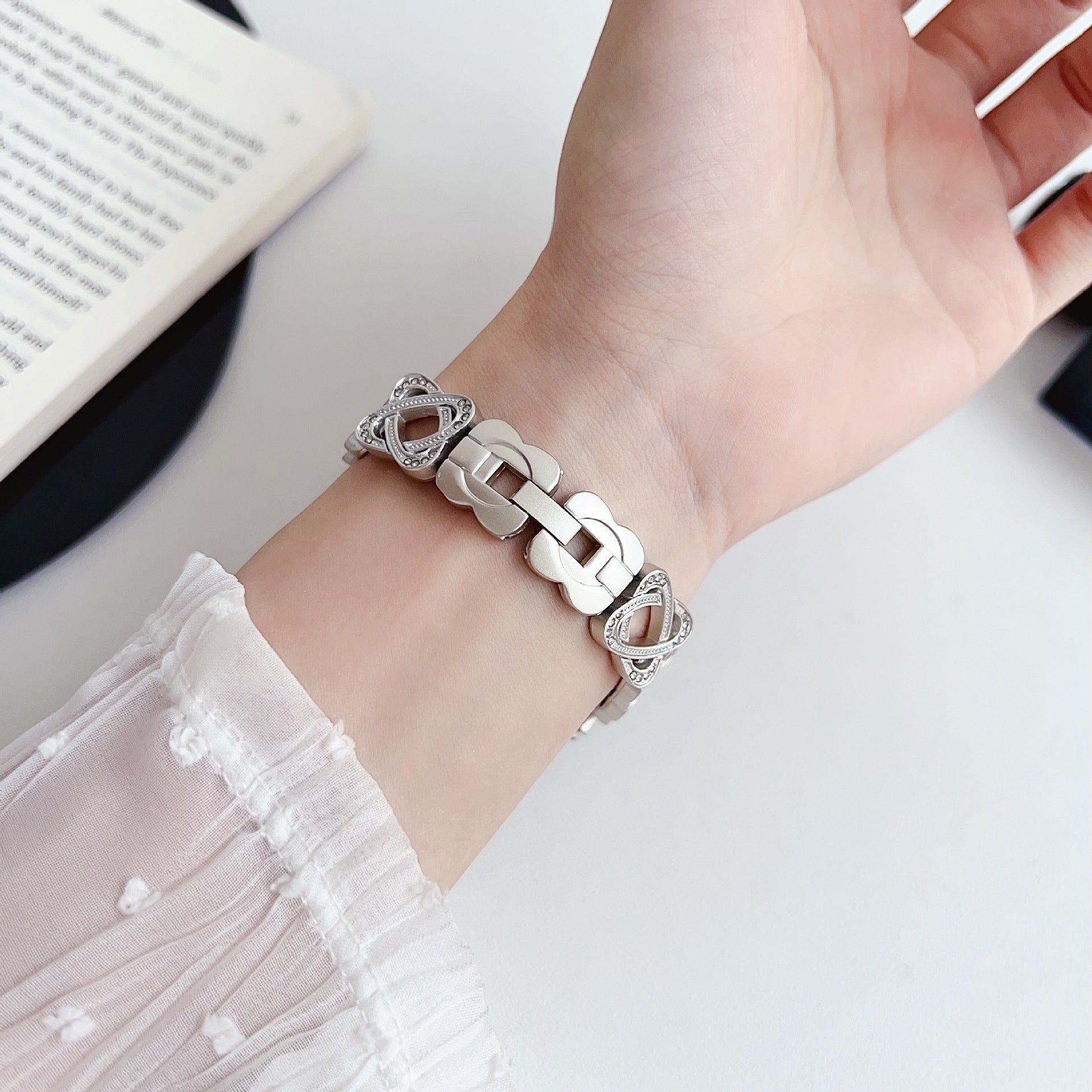 Pulseira para Apple Watch em metal prateado com malhas entrelaçadas, motivo de nó infinito cravejado de zircónias, fecho de encaixe ajustável, modelo Zergone