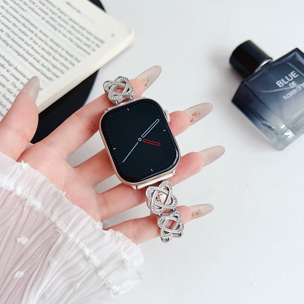 Pulseira para Apple Watch em metal prateado com malhas entrelaçadas, motivo de nó infinito cravejado de zircónias, fecho de encaixe ajustável, modelo Zergone