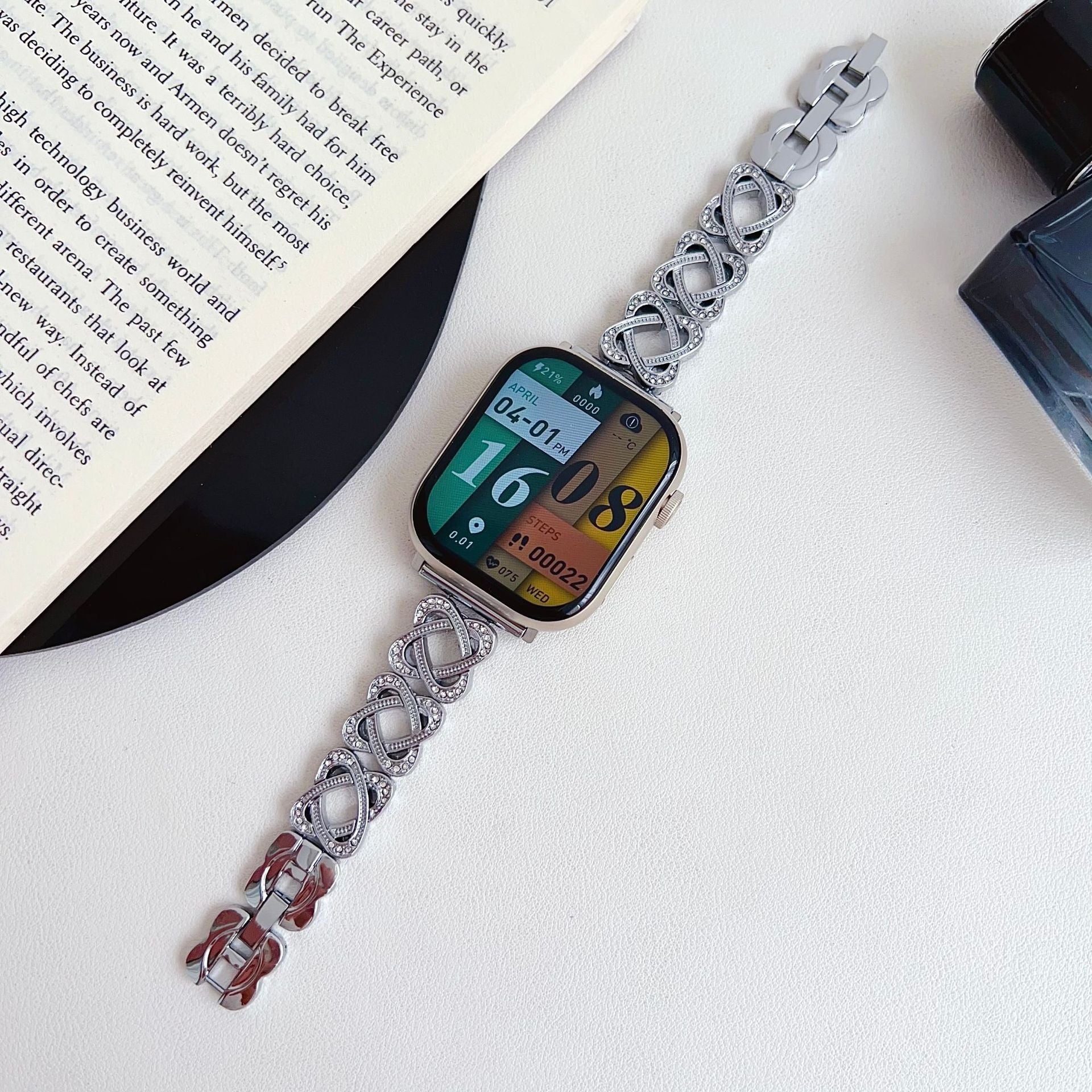 Pulseira para Apple Watch em metal prateado com malhas entrelaçadas, motivo de nó infinito cravejado de zircónias, fecho de encaixe ajustável, modelo Zergone