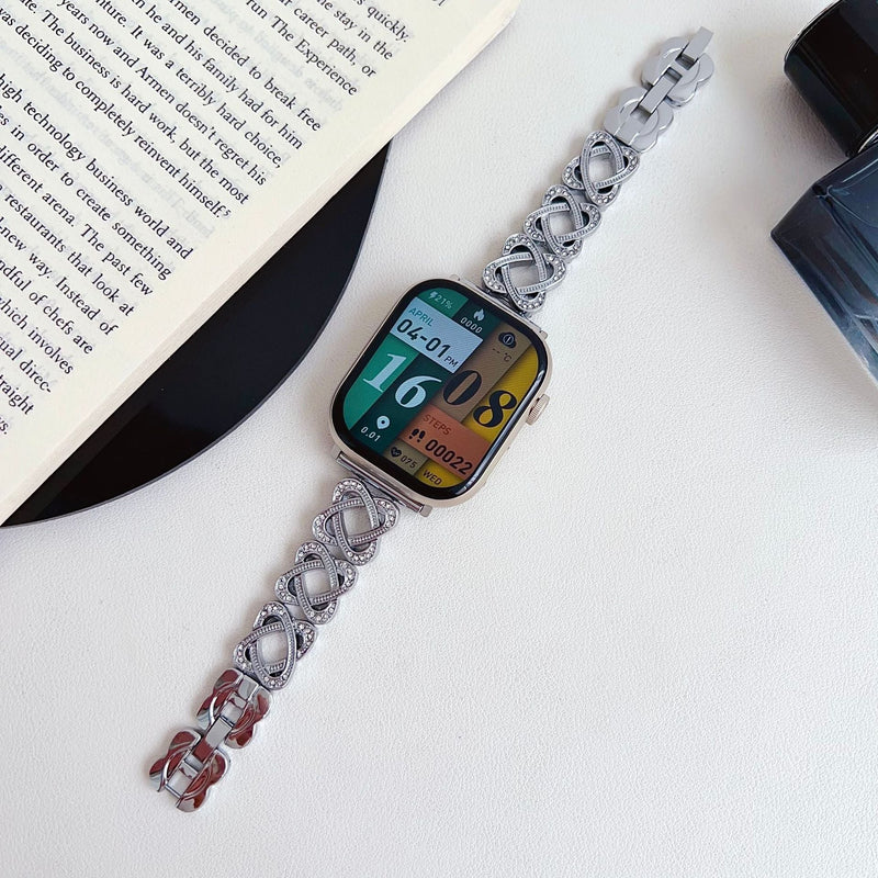 Pulseira para Apple Watch em metal prateado com malhas entrelaçadas, motivo de nó infinito cravejado de zircónias, fecho de encaixe ajustável, modelo Zergone