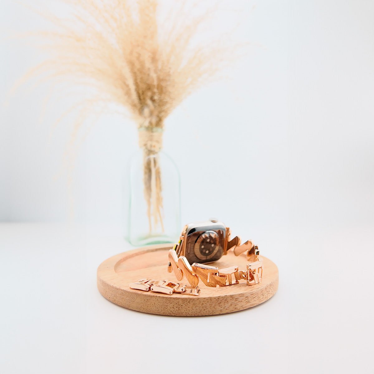 Bracelet spirale en acier doré pour Apple Watch, design moderne pour femme sur socle en bois clair.