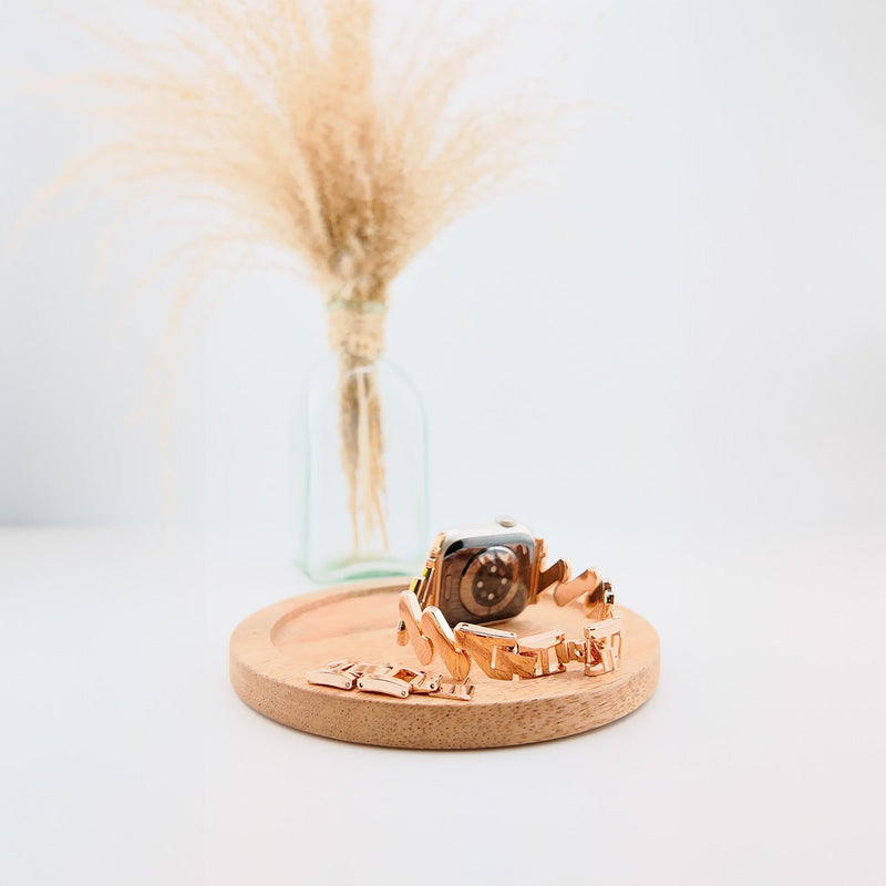 Bracelet spirale en acier doré pour Apple Watch, design moderne pour femme sur socle en bois clair.