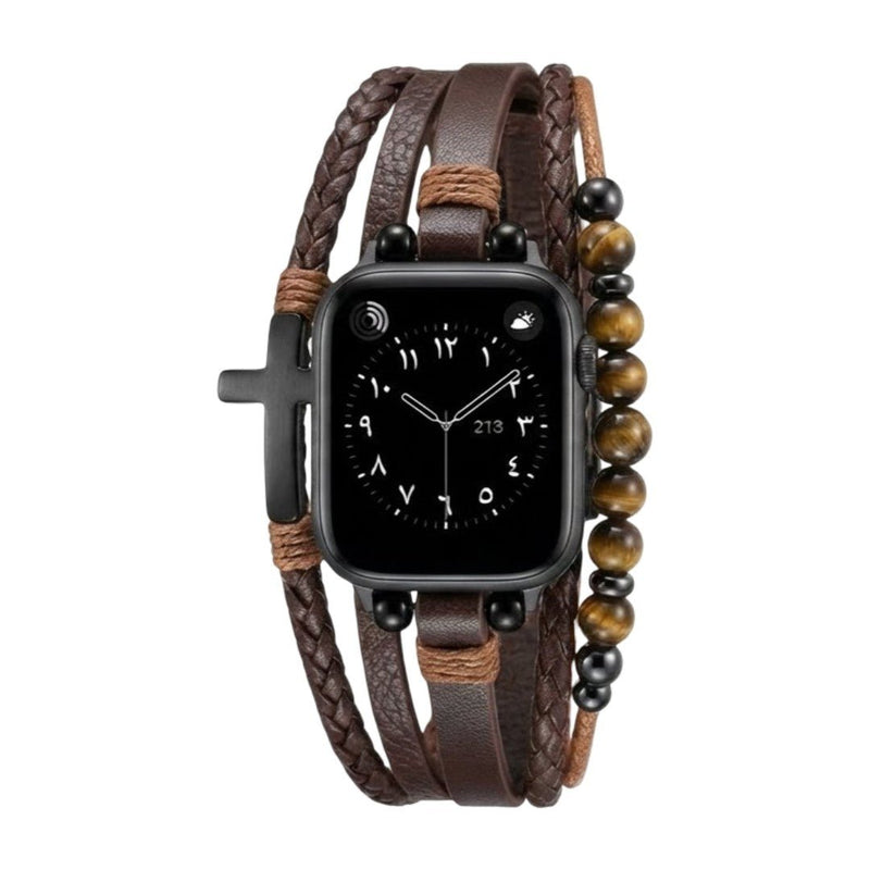 Bracelet multi-rangs en simili cuir vegan marron avec perles œil de tigre et croix noire attachées à une Apple Watch noire.