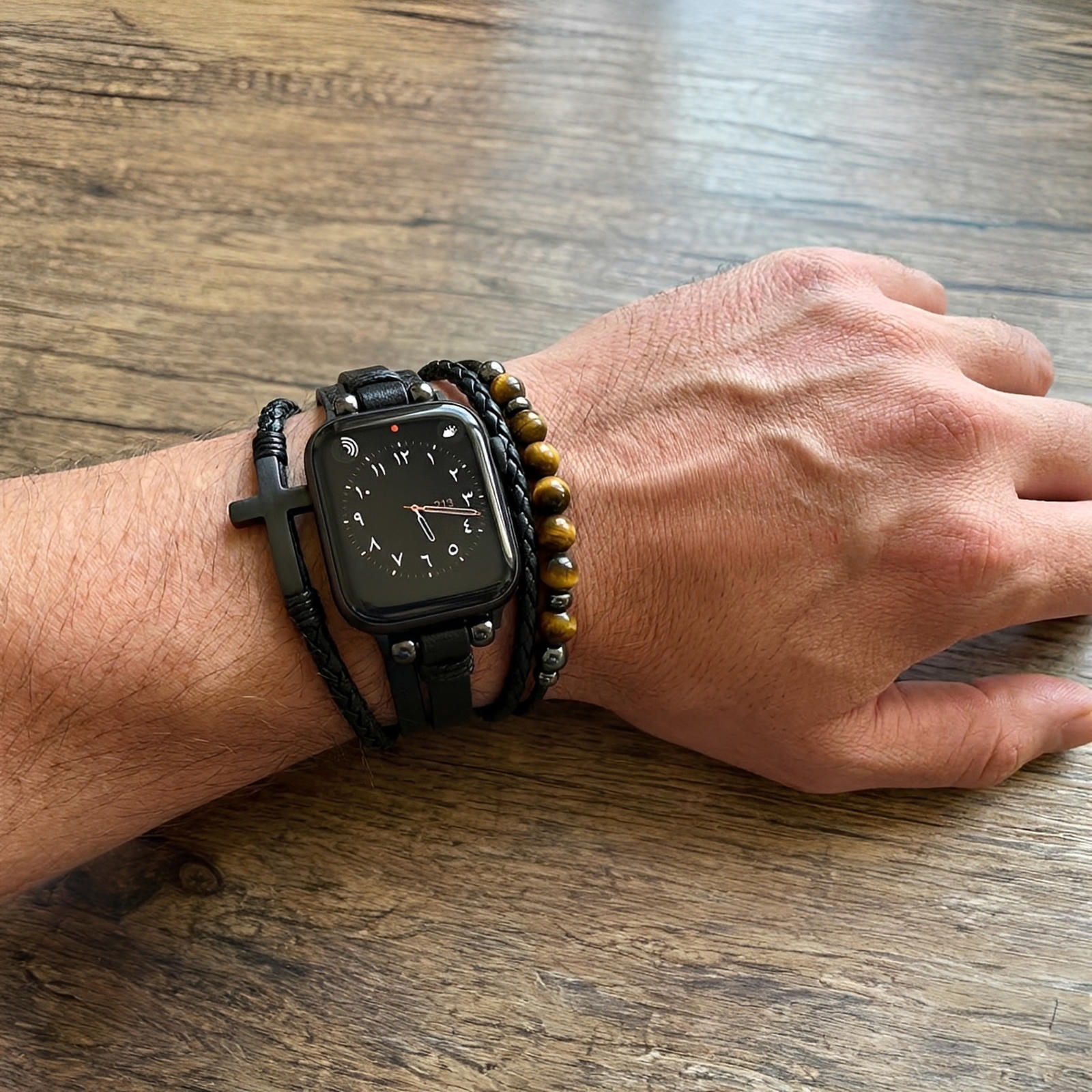 Bracelet multi-rangs noir en simili cuir vegan avec perles œil de tigre marron et croix noire, fermé par fermoir ajustable.