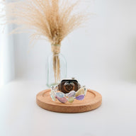 Bracelet pour Apple Watch femme avec plumes colorées pastel en résine sur fond clair minimaliste.